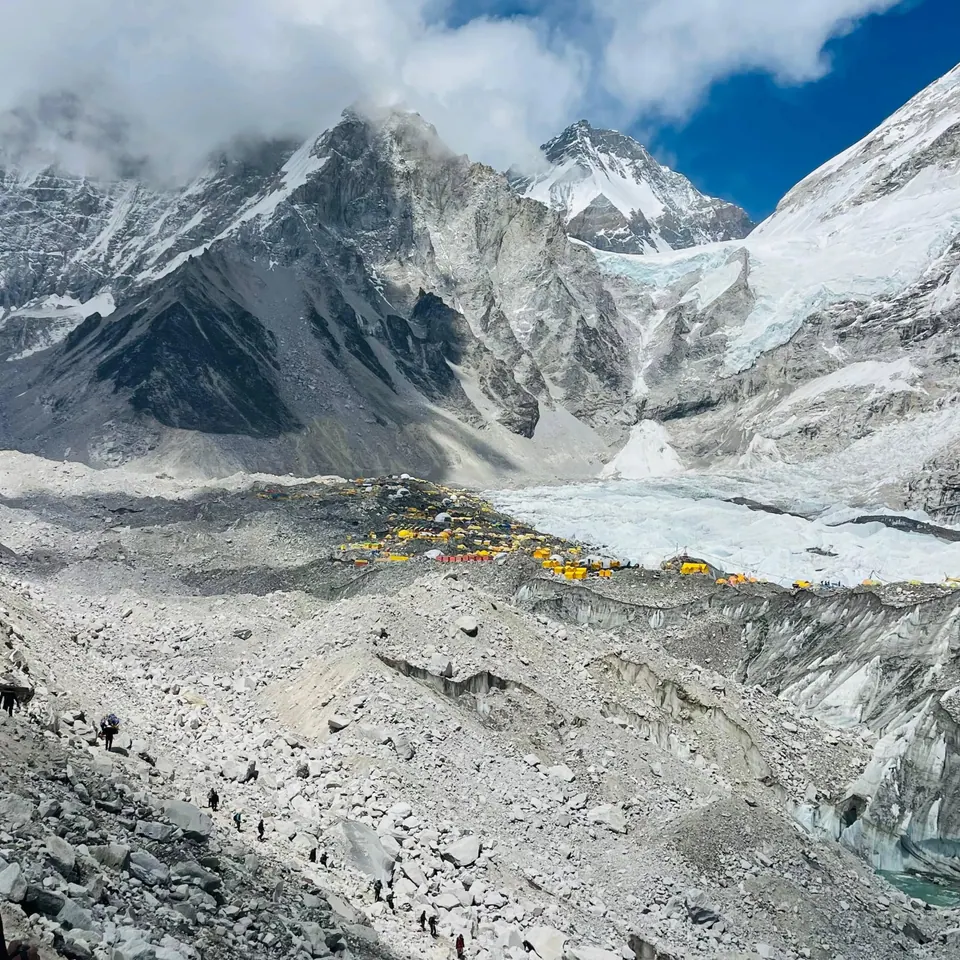 Yellow expedition tents below the icefall and trekkers on the rocky glacier trail, Everest Base Camp, Khumbu Glacier
