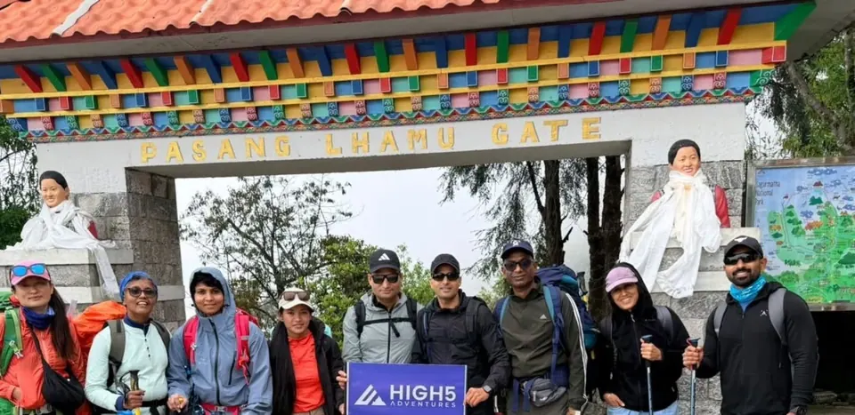 Trekkers holding a High 5 Adventures banner under the Pasang Lhamu Gate in Lukla, May 2026
